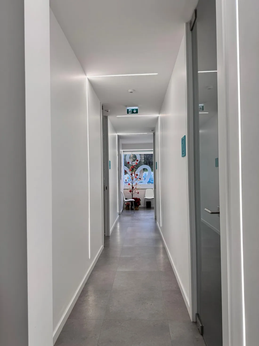 Corredor de acesso aos gabinetes, com luz natural ao fundo.