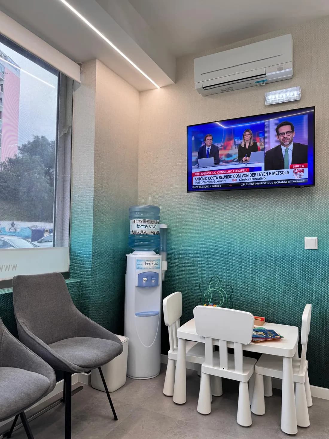 Espaço para crianças, com mesa pequena junto à parede em degradê turquesa.