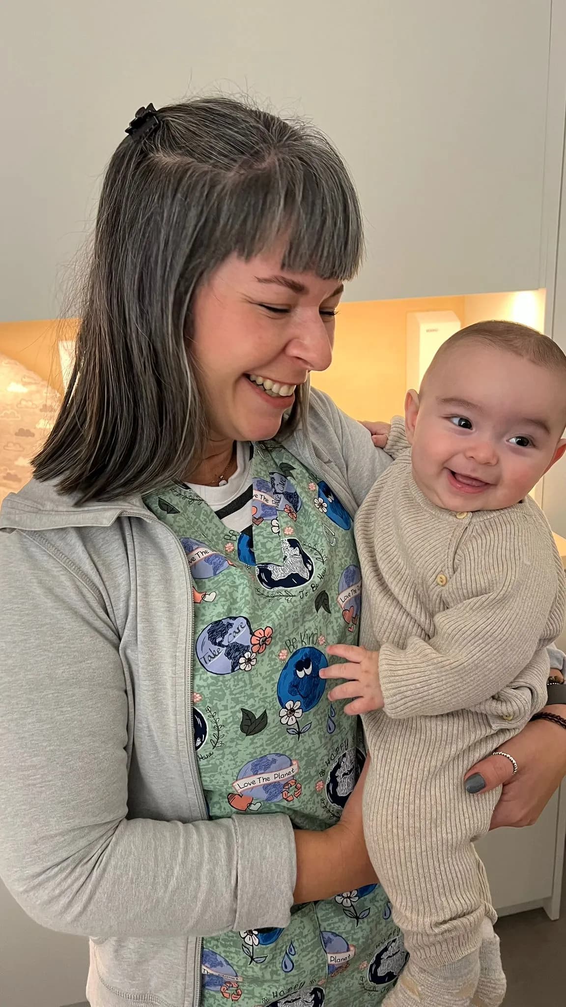 Mãe a segurar o seu bebé, ambos a sorrir, na Clínica Almada Care.
