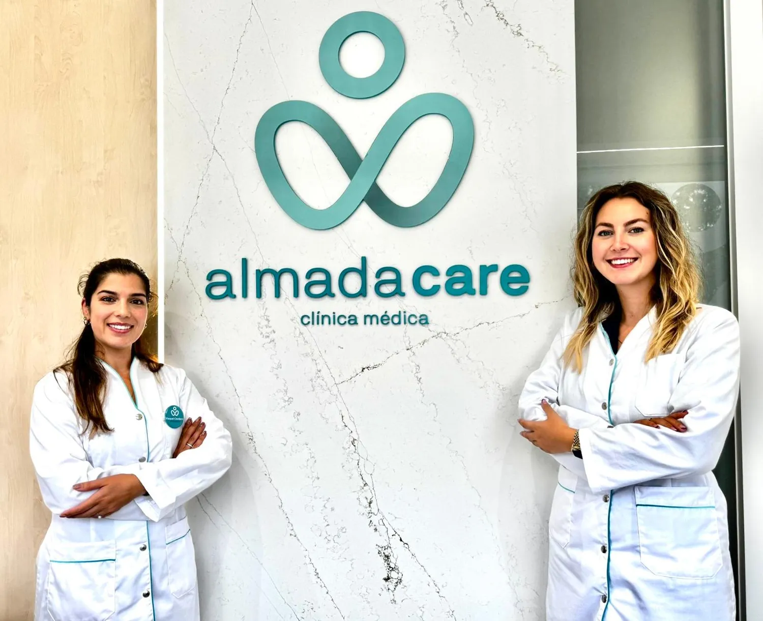 Duas profissionais da Almada Care lado a lado junto ao logótipo.